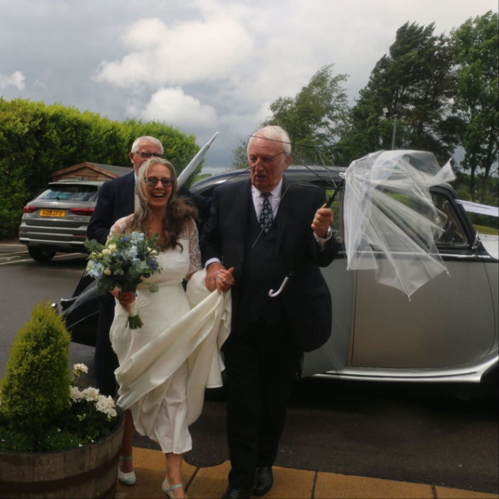 Bride and groom beside their wedding car