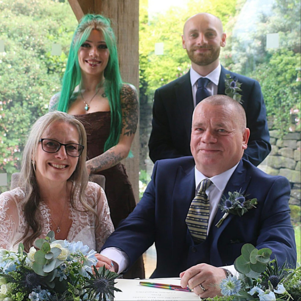 Bride and groom with wedding flowers signing the register
